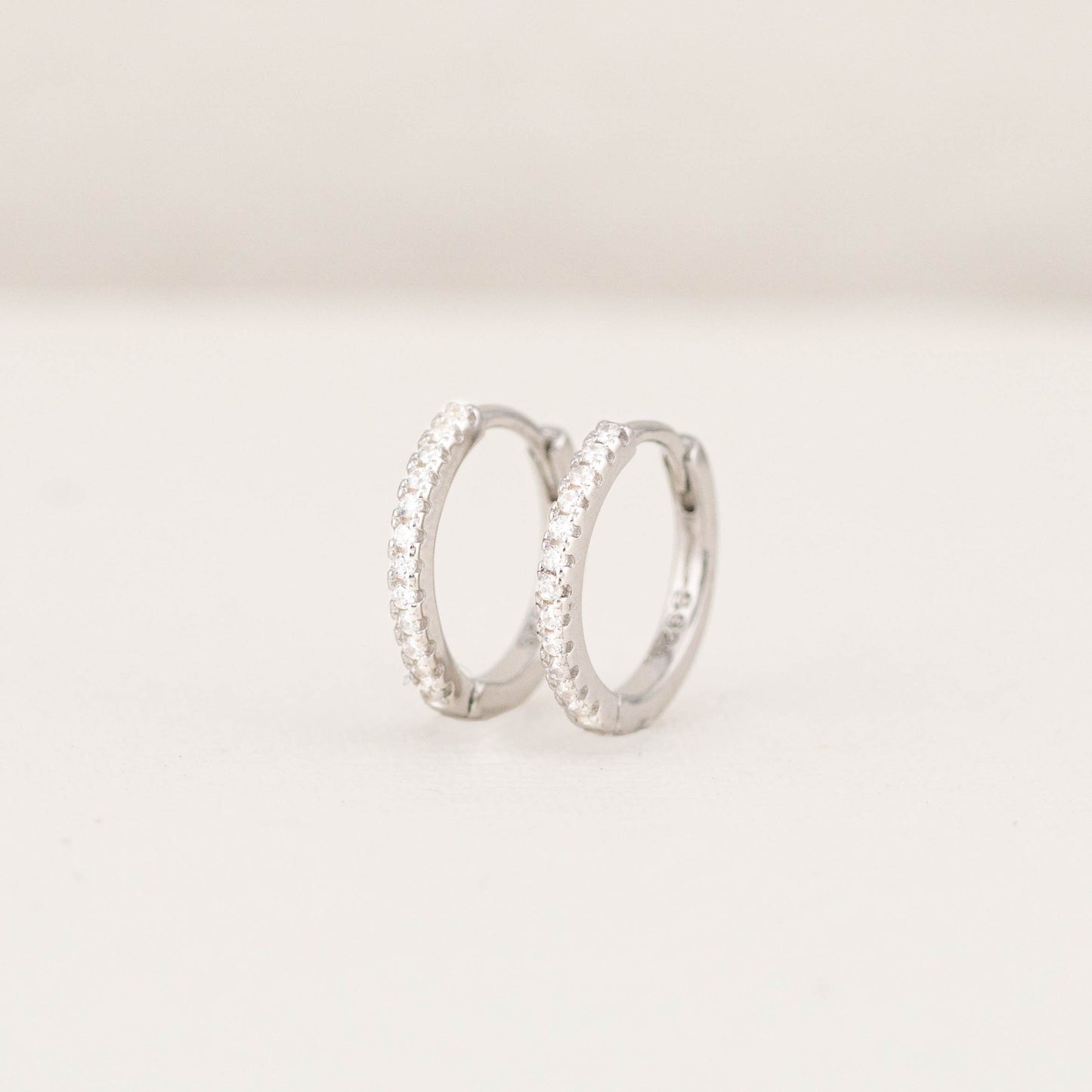 Front view of thin diamond silver hoop earrings, showing the small sparkling stones.