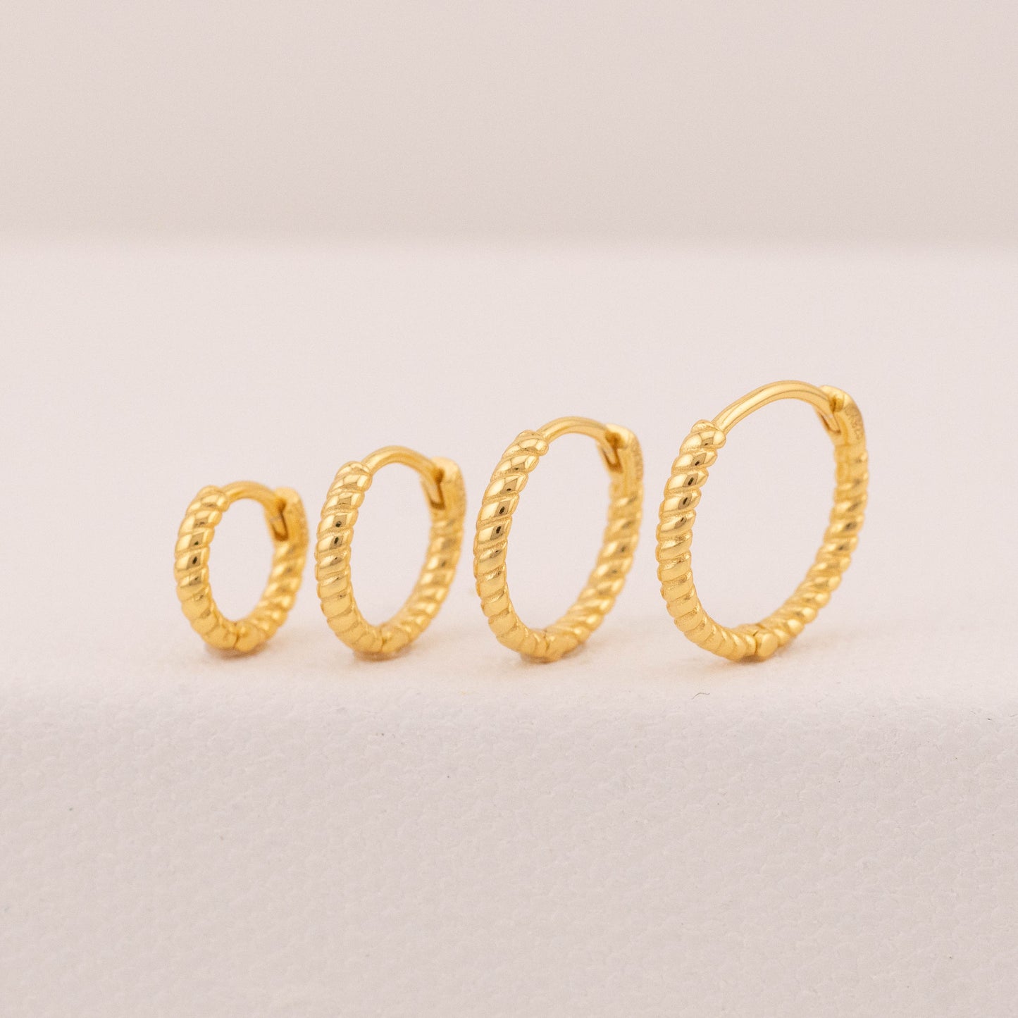 Mini huggie hoop earrings on stand, angled view showing croissant texture, suitable for 2 holes.